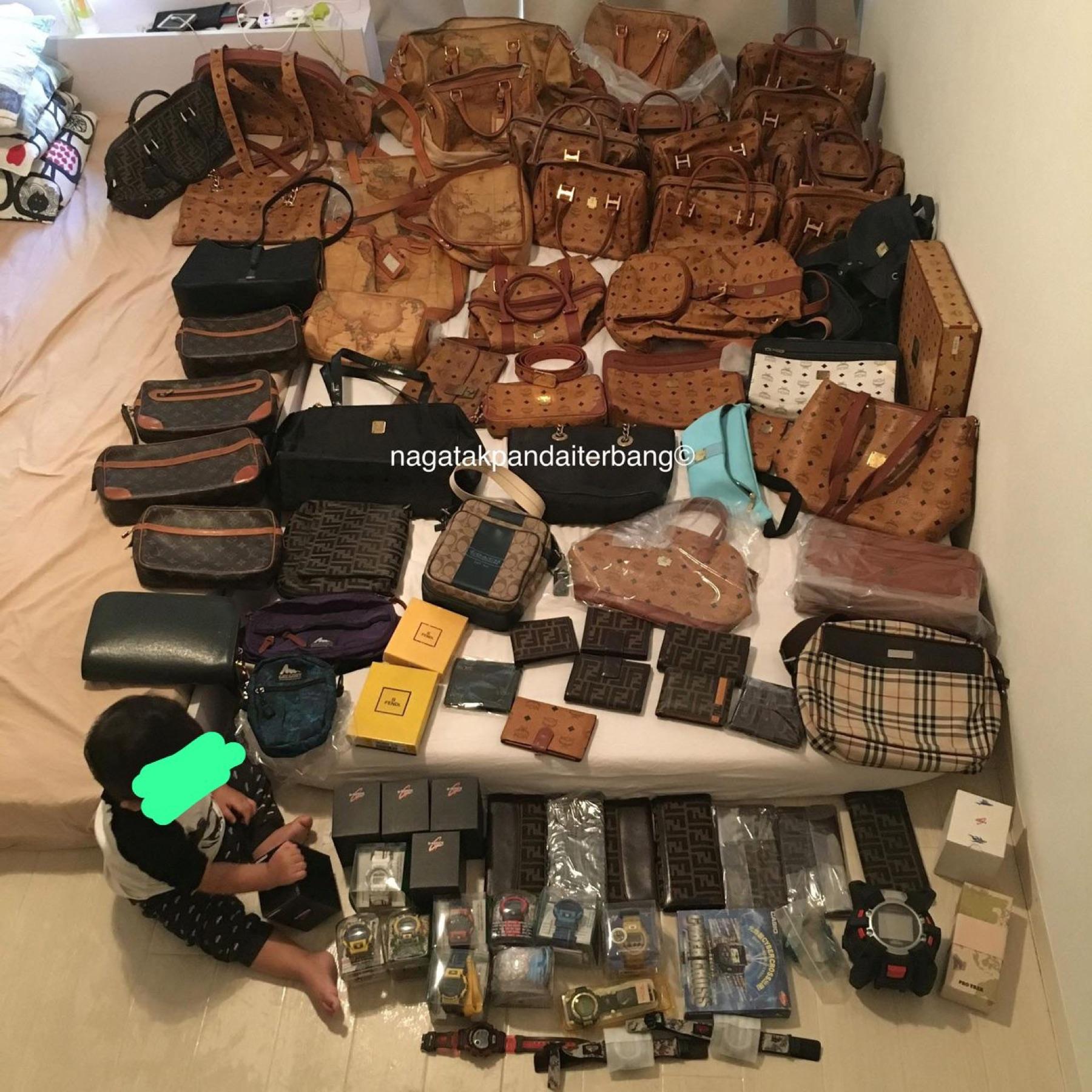 Bed covered in vintage MCM cognac bags, Alviero Martini map bags, Fendi wallets, Burberry bag, G-Shock watches and a small child