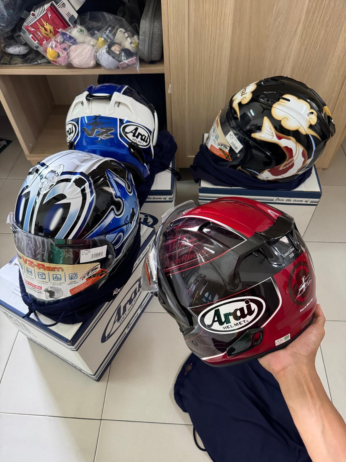 Four Arai helmets including a signed blue VZ-Ram, a black koi fish design and a red Taira Racing limited edition