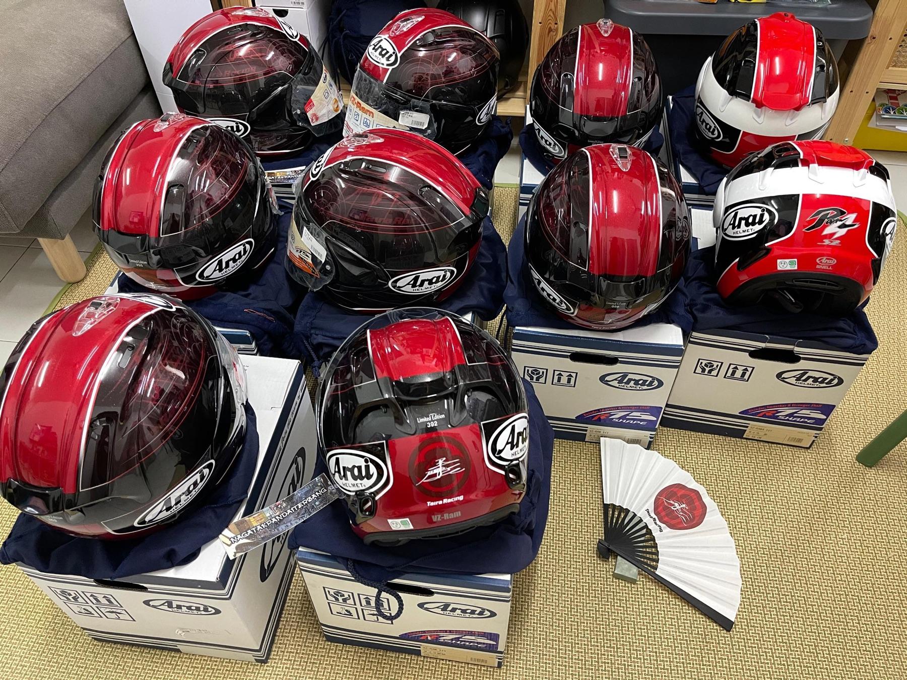 Ten red Arai VZ-Ram Taira Racing limited edition helmets on Arai boxes with a numbered fan