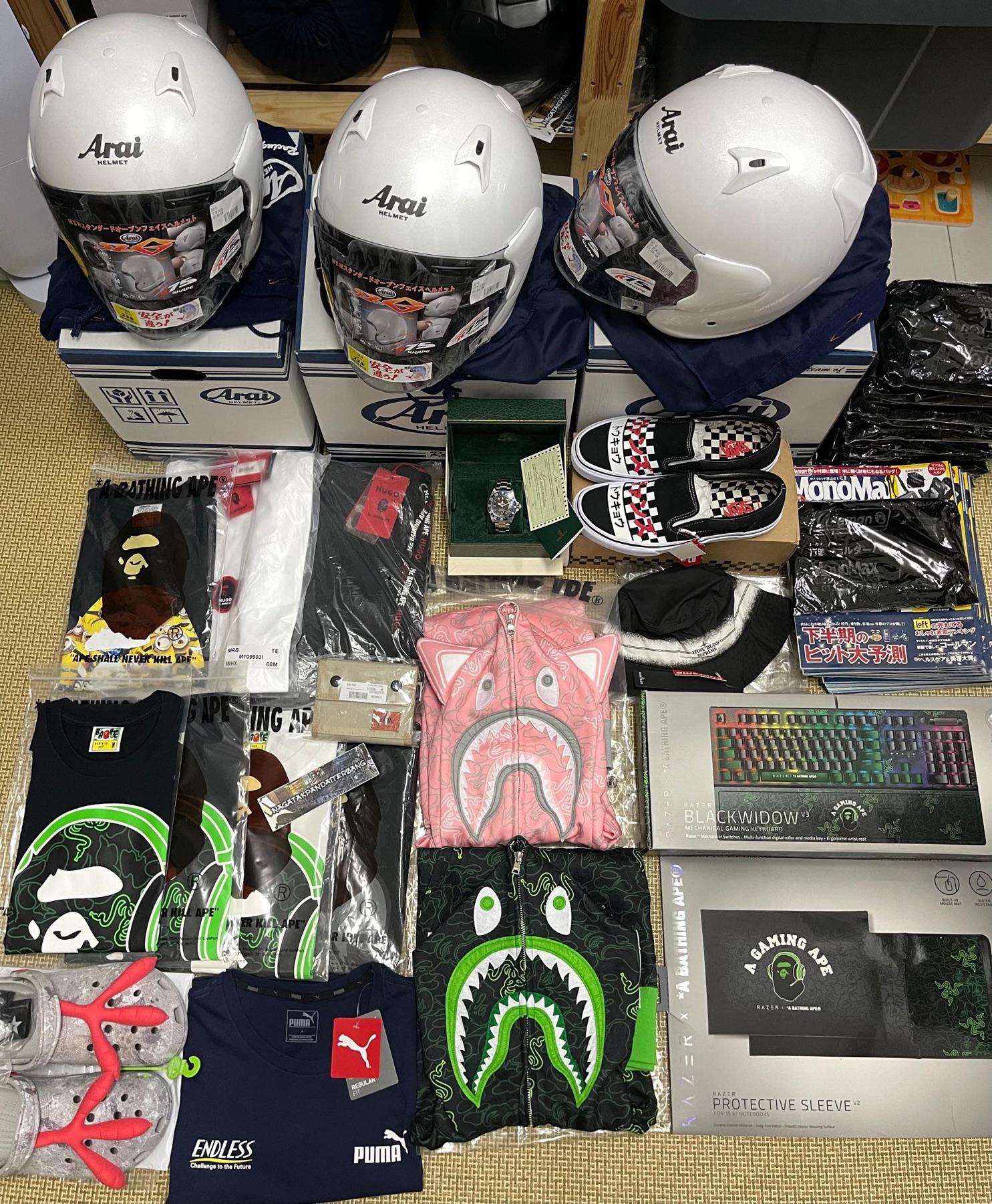 Three white Arai helmets, a Rolex in green box, Vans Tokyo checkerboard, BAPE Razer keyboard, pink and green shark hoodies