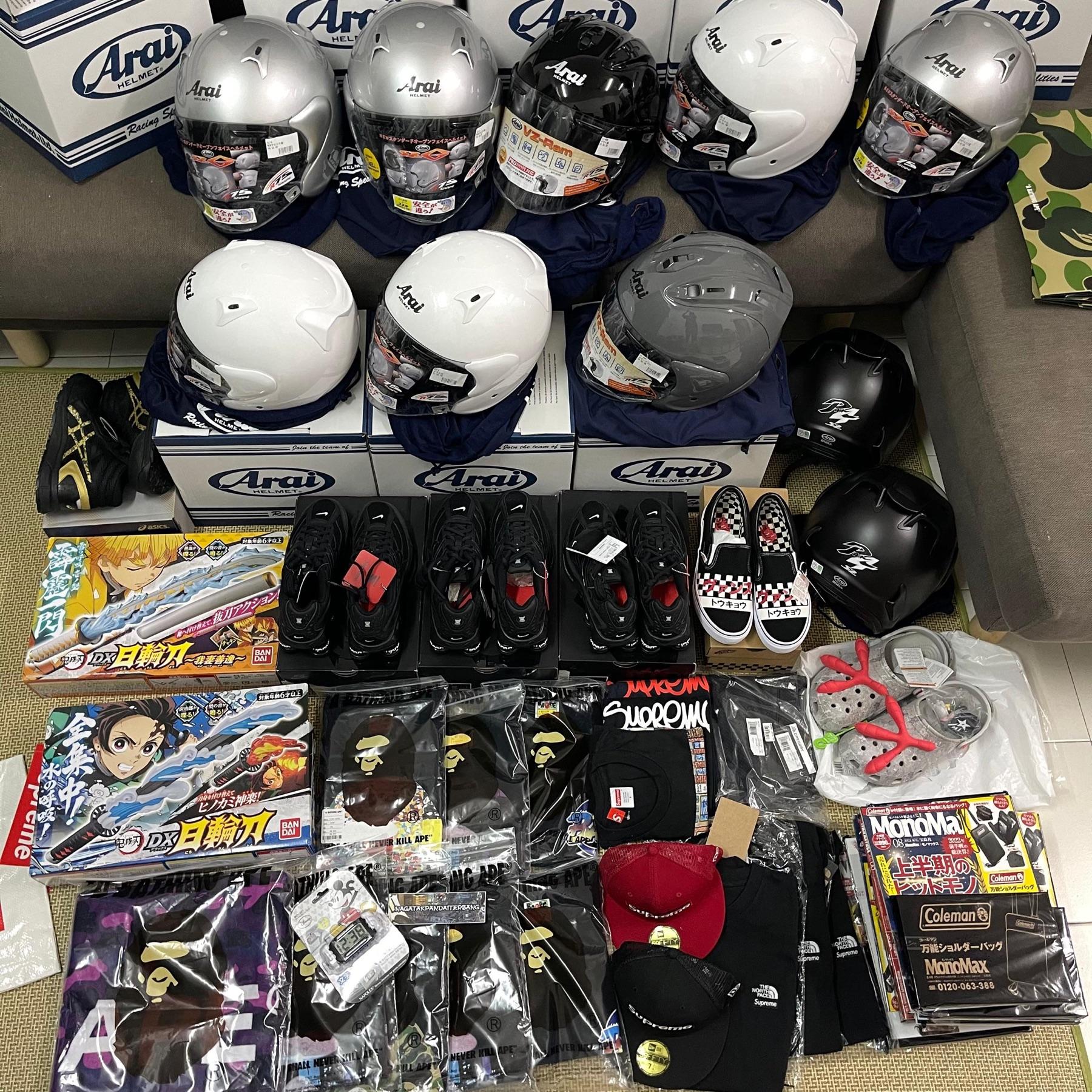 Eight Arai helmets on boxes with Nike sneakers, Vans, Demon Slayer toy swords, BAPE tees and Supreme caps
